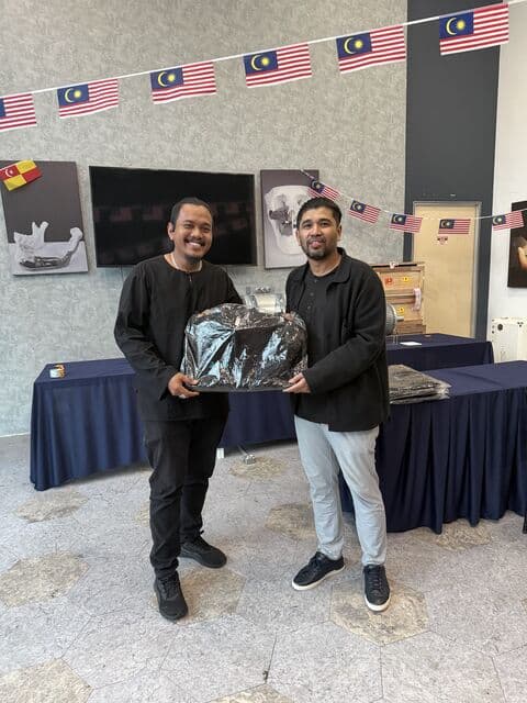 Team member in a black shirt receives a 3D Gens bomber jacket