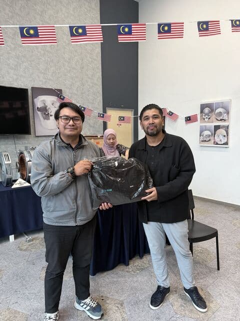 Team member in a cap receives a 3D Gens bomber jacket