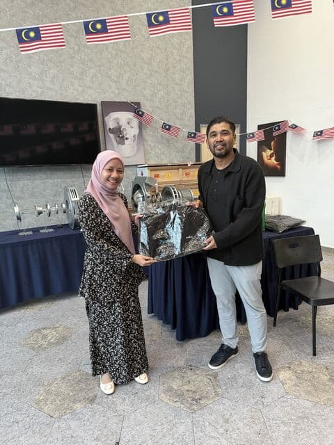 Team member in a patterned hijab receives a 3D Gens bomber jacket