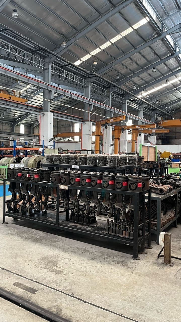 Engine pistons and locomotive components arranged on the KTMB Central Workshop floor, representing parts targeted for 3D printing solutions