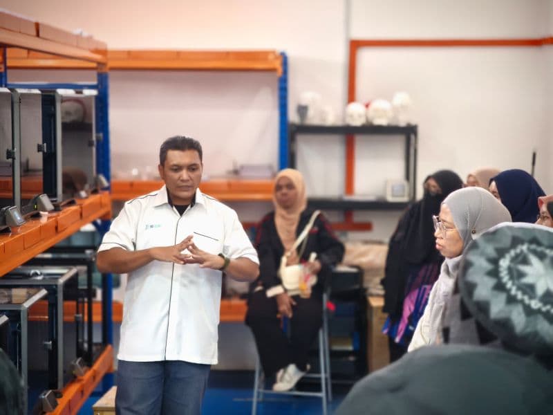 A 3D Gens trainer explains polymer 3D printing operations to Politeknik Seberang Perai students in the production area
