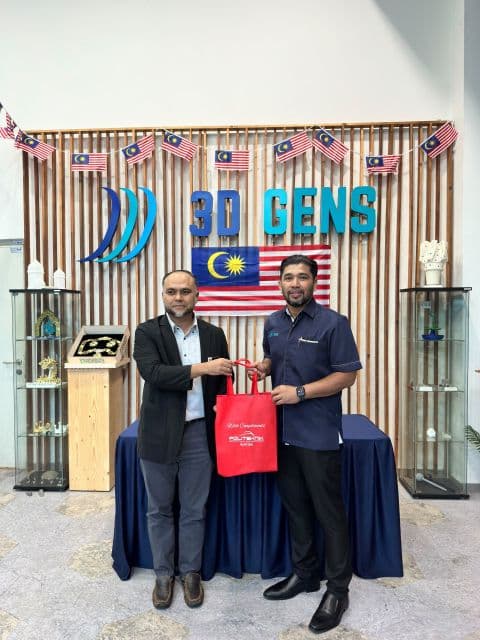 Two representatives exchange a red gift bag at the 3D Gens office